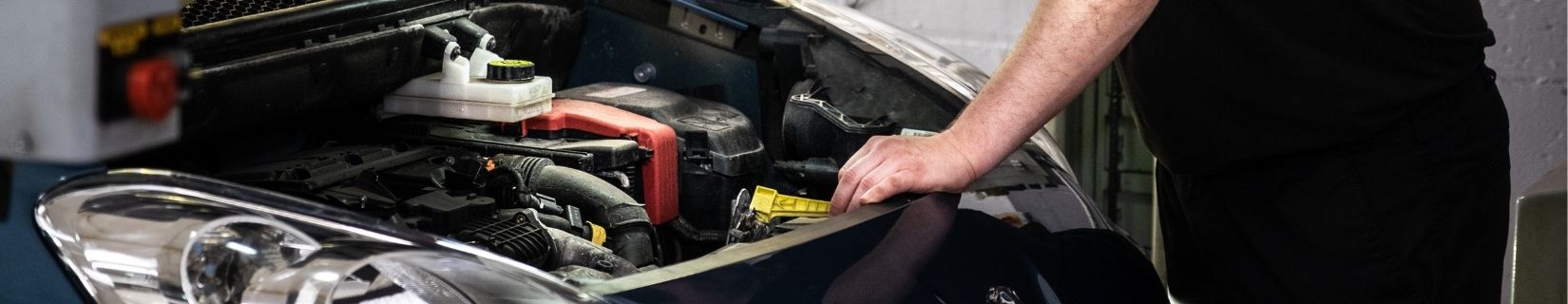 mechanic servicing a car with the bonnet lifted on the car