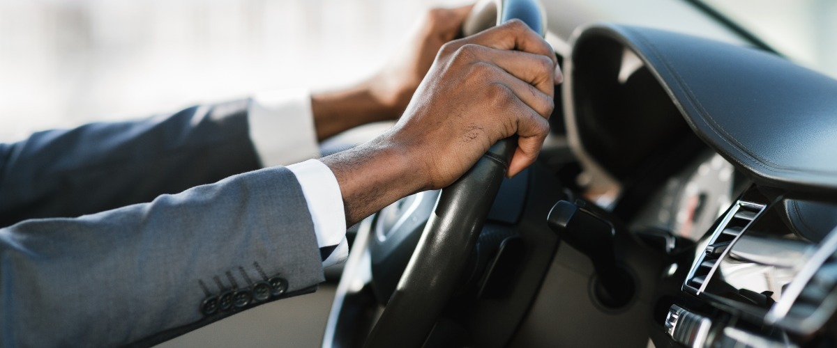 close up of man with hands on steering wheel