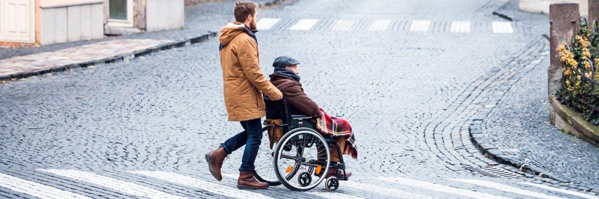 Young man pushing older man in wheelchair