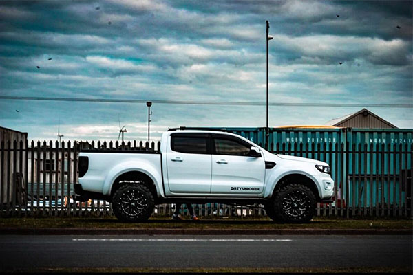 Image of a white pick-up truck from the side underneath a cloudy sky