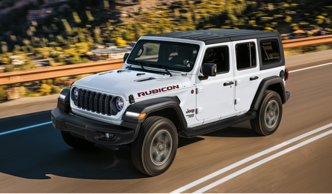 White Jeep Wrangler with a black roof pictured driving on a road with a landscape background