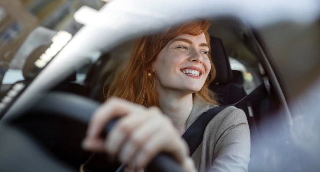 A red-haired young driver at the wheel of a car.